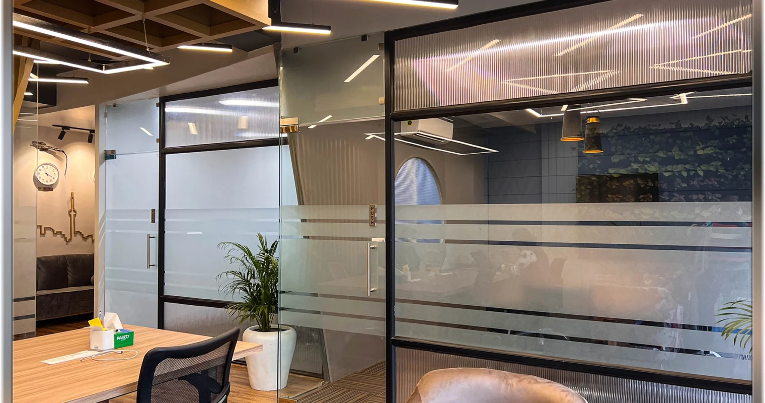 Corporate office reception at Rajouri Garden Delhi with glass partitions, modern lighting and seating by commercial architects expert Amartya architects in Delhi NCR.