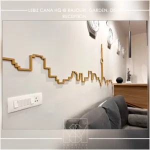 Office reception wall detail with custom metal artwork and seating, designed by commercial interior designers in Delhi