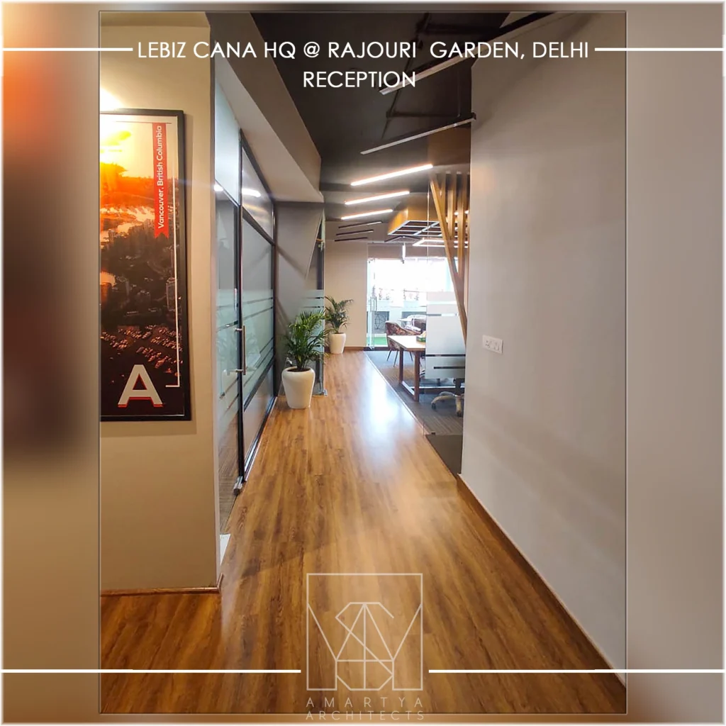 Modern office corridor with wooden flooring, glass partitions and linear lights, designed by commercial interior designers (Amartya architecrs) in Delhi NCR.