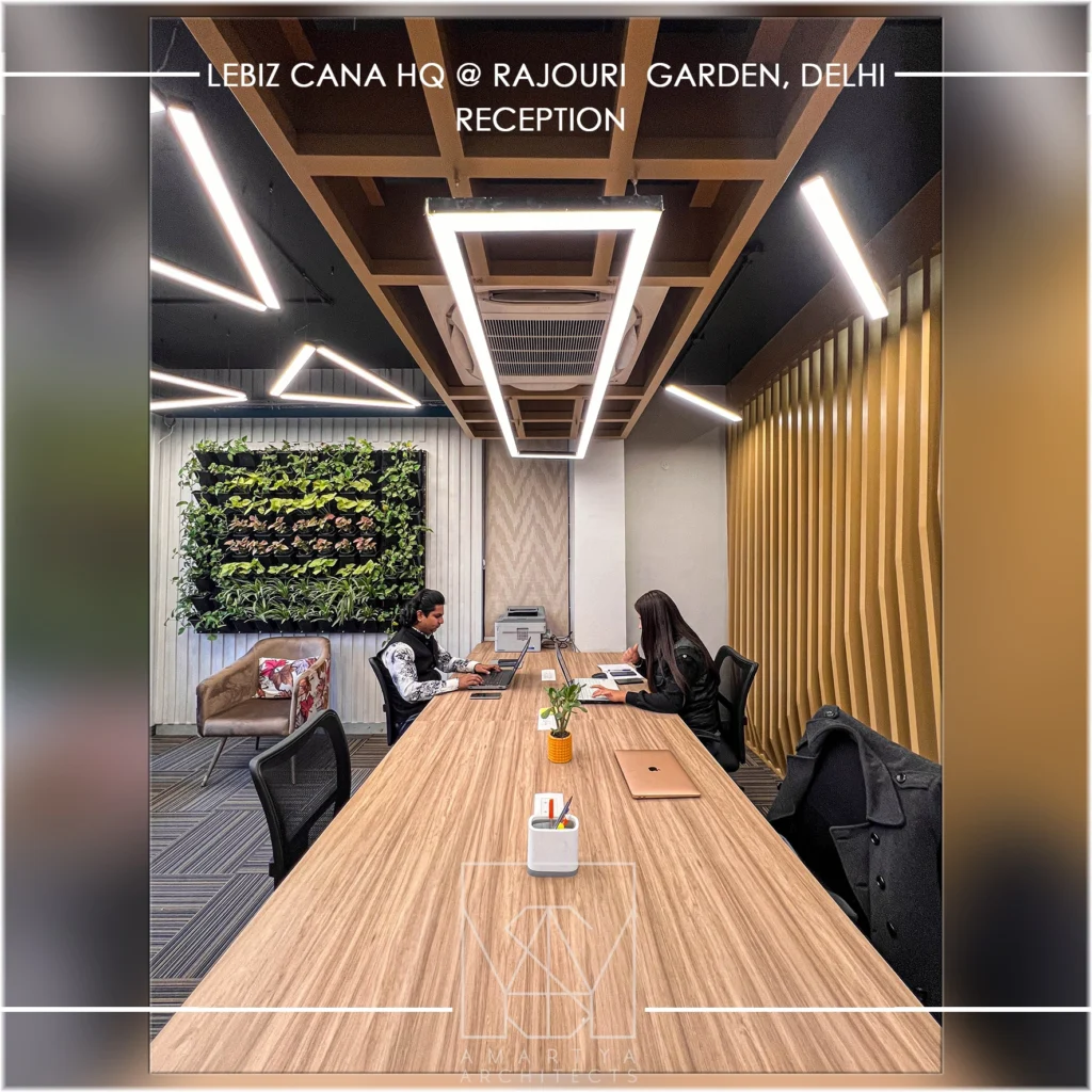 Contemporary office meeting room with long wooden table, green wall and designer lighting by interior design firms in Delhi NCR.