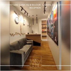 Office reception waiting area with modern sofa seating, wall décor and warm lighting designed by interior designers in Delhi.