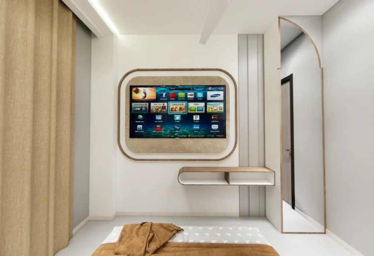 Bedroom TV wall design by Amartya Architects featuring wall-mounted smart TV, curved wooden panel detailing, floating console, and arched mirror in a modern bedroom interior.