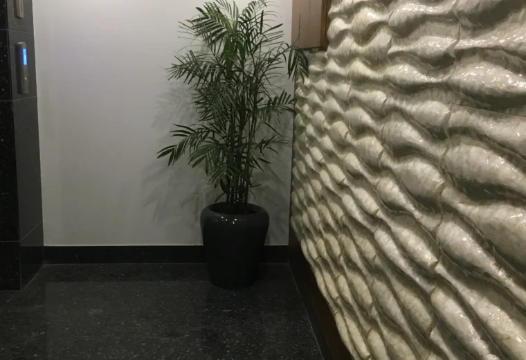 Indoor corridor design with textured 3D wall cladding, decorative potted plant and modern lighting by Amartya Architects | contemporary interior detailing