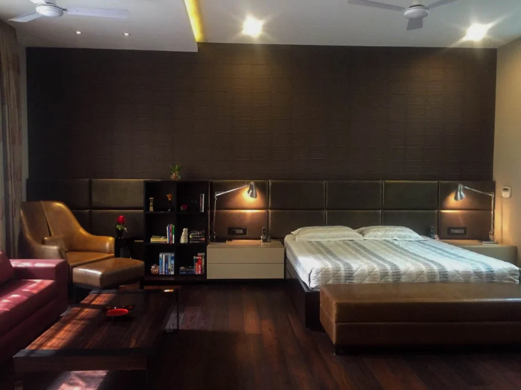 Luxury master bedroom interior with upholstered headboard wall, wooden flooring, ambient lighting and custom furniture, designed by a professional home interior designer near me.