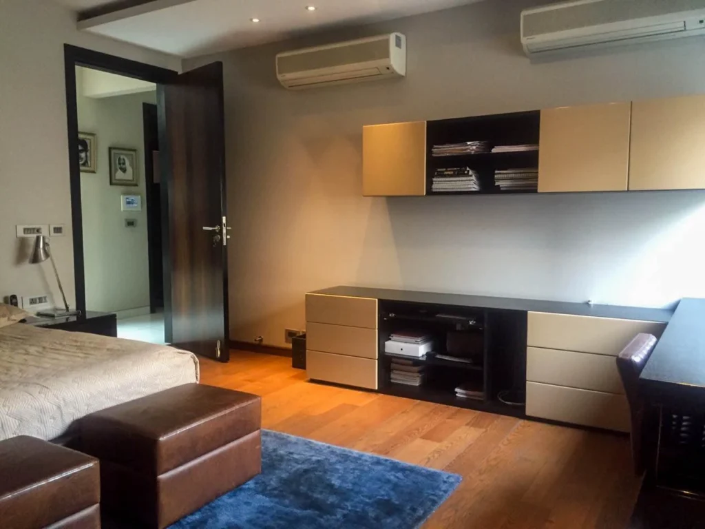 Modern bedroom interior design with integrated study unit, custom storage cabinetry, wooden flooring and soft lighting, designed by a bedroom interior designer near me in Delhi NCR.