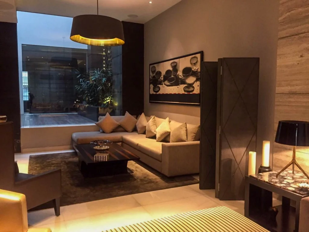 Stylish lounge interior with neutral sofas, designer pendant light, layered lighting and textured finishes, created by residential interior designers near me offering luxury interior design solutions.