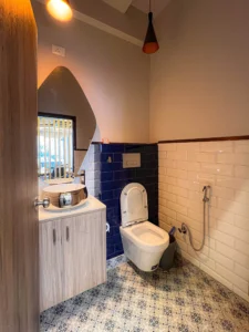 Modern washroom interior with patterned tiles, wall mounted fixtures and ambient lighting by interior designers Amartya architects.