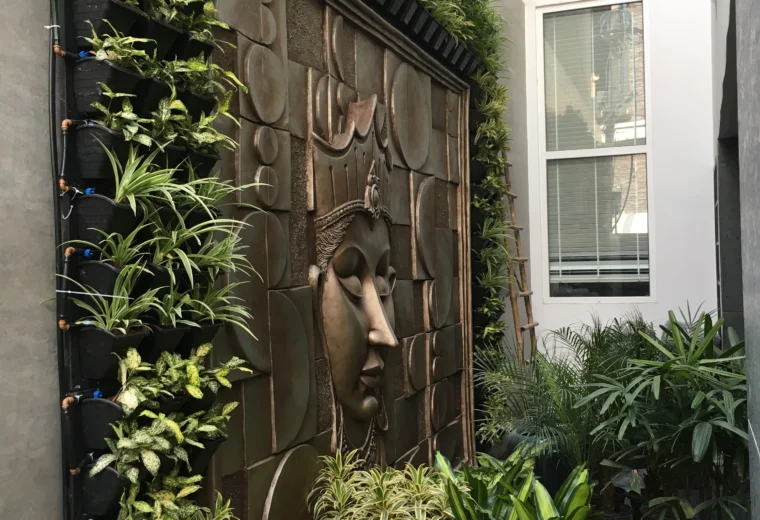 Luxury courtyard landscape with Buddha wall art, vertical garden, ornamental plants and serene outdoor design by Amartya Architects | residential landscape design India