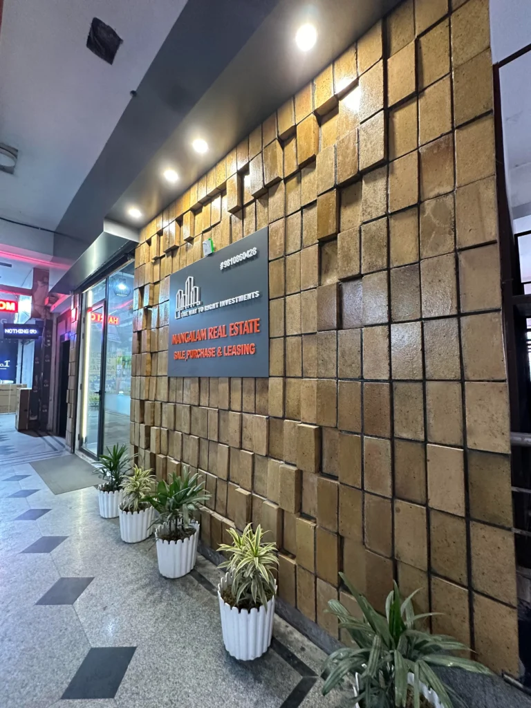 Commercial office exterior wall cladding with textured blocks, signage and planters designed by Amartya Architects for real estate workspace. |