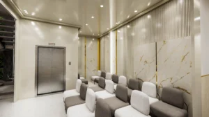 Elegant hospital waiting area interior featuring modular seating, elevator lobby, and modern ceiling design by Amartya Architects
