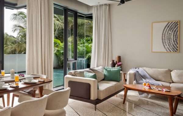 Modern open-plan living and dining area with wooden furniture, large glass windows, soft neutral tones and natural lighting designed by Amartya Architects, recognized among the best interior designers for luxury home interiors